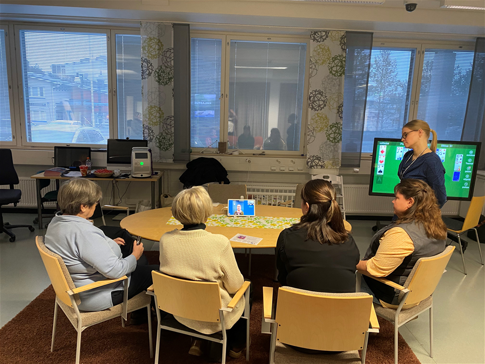 Marjo Jussila seisoo luokkahuoneessa ryhmätyöpöydän vieressä.