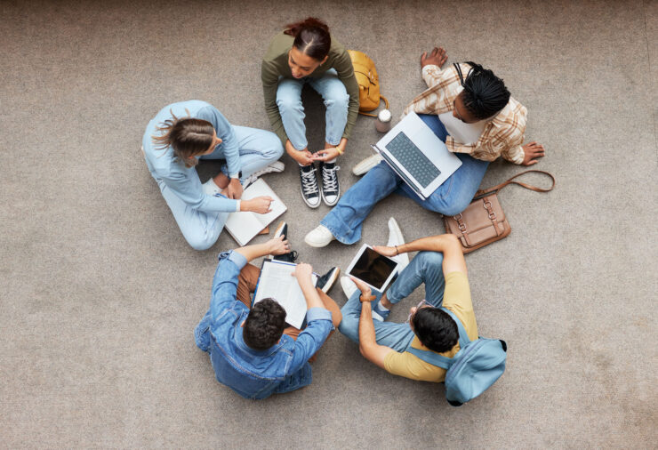 Five students are sitting in a circle and studying together.