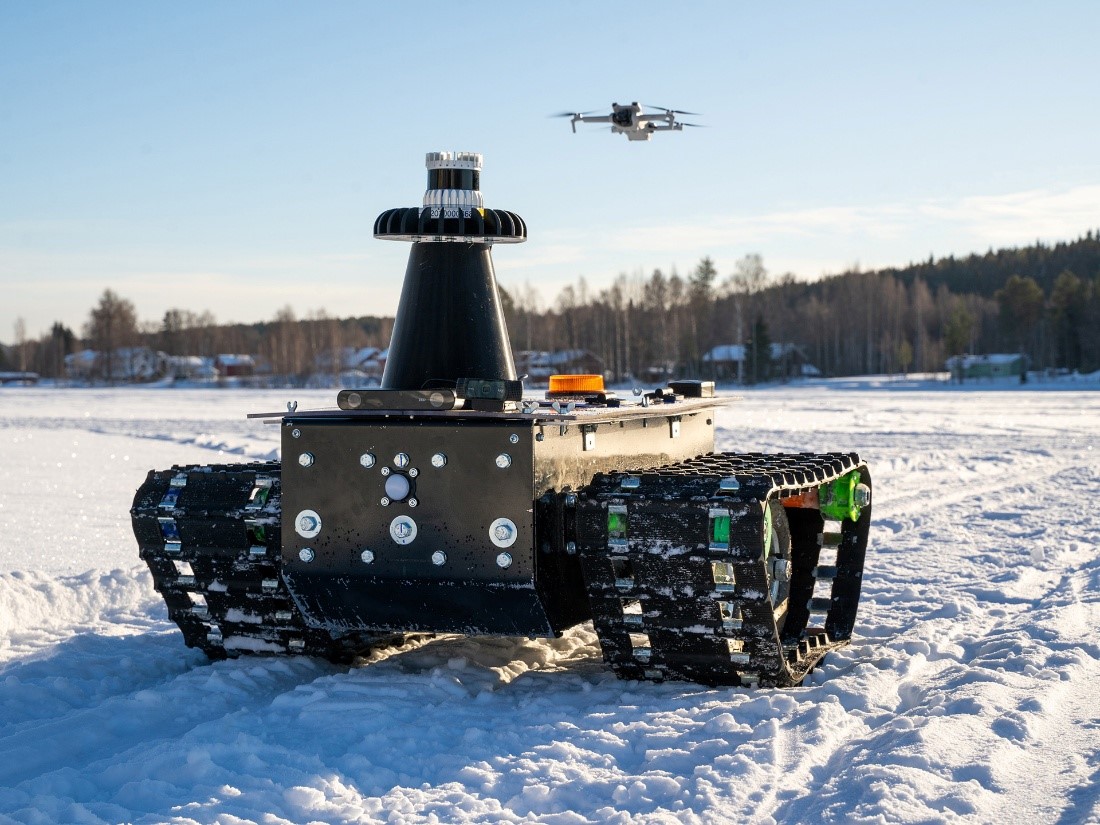 Drone ja prototyyppi tela-ajoneuvosta lumisessa maisemassa
