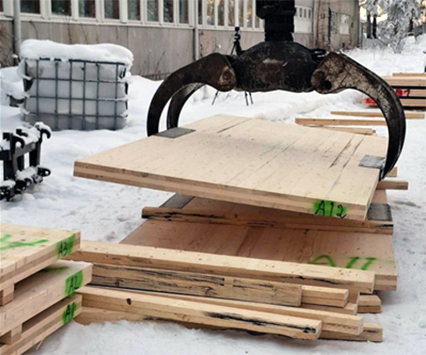 Koneen kuormakoura nostaa suurta CLT-levyä.